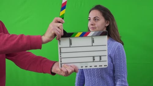 Clapperboard in Male Caucasian Hands Clipping Leaving and Young Woman Looking at Camera Portrait of