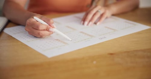 Woman Writes on Calendar Page with Pen
