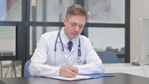 Doctor Writing on Clipboard in Hospital Office