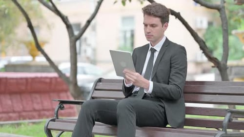 Businessman using Tablet while Sitting on Bench