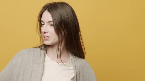 Enthusiastic Woman Dancing Cheerfully on Yellow Background