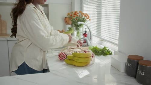 Mujer sacando productos frescos de una bolsa orgánica en casa