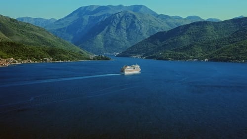 Aerial view shows a white cruise ship cutting deep blue water in Montenegro's Bay of Kotor,