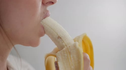 Close Up of Lady Savoring Banana in Bright Relaxed Indoor Environment
