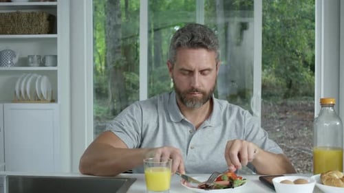 Man enjoys breakfast at home near window