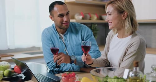 Couple Smiling and Toasting with Wine in Kitchen