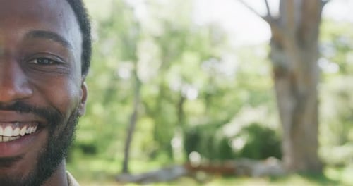 Portrait of happy african american man looking at camera in park, slow motion