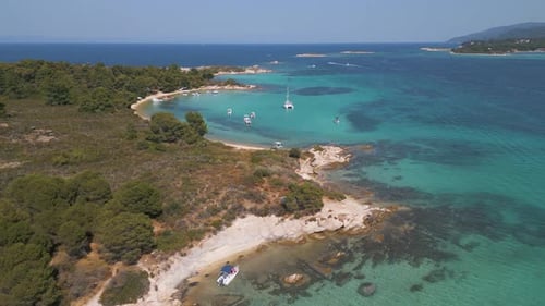 Aerial View of a Tropical Beach with Turquoise Waters Anchored Boats and Pine Forest Stunning