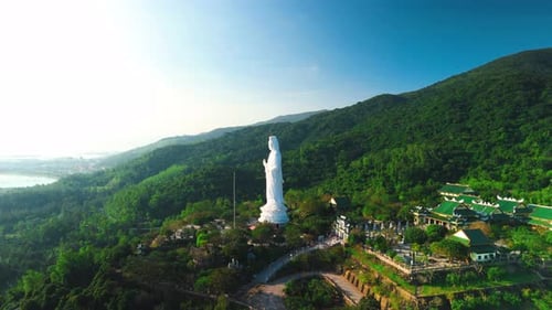 Towering White Lady Buddha Statue Perched on Green Mountainside Revealing Panoramic Landscape with