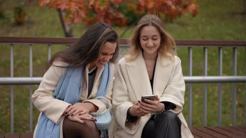 Two Women Looking at Mobile Phone in Park