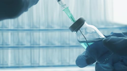 A Doctor is Drawing Up Vaccine From Phial Bottle and Filling Syringe Injection for Vaccination
