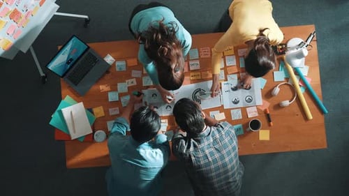 Bird's Eye View of Creative Team Brainstorming Around a Large Wooden Table