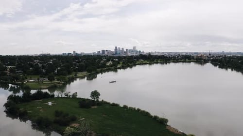 Drone shot pushing over Sloan Lake towards Denver's downtown skyscrapers.