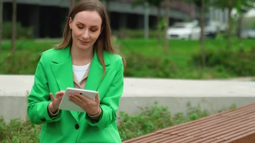 Woman Works Online Using a Tablet Computer A Woman in a Green Jacket with a Modern Tablet in Her