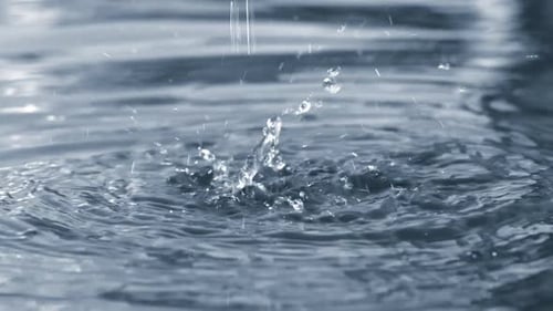 Beautiful Drops and Streams of Water Falling Into the Blue Pure Water of the Fountain