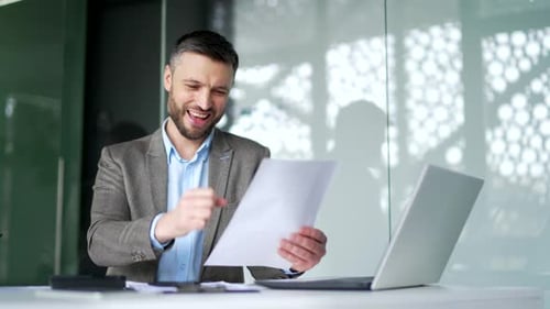 Excited Man Reads Good News at Office Desk