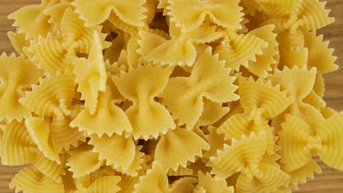 A
massa em forma de arco é despejada em uma tigela de vidro transparente contra uma tábua de madeira de carvalho. Vista superior.