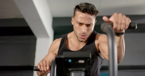 Exercising on stationary bike, man in gym focusing on intense workout