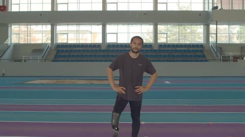 Man with Prosthetic Leg Stands on Indoor Track