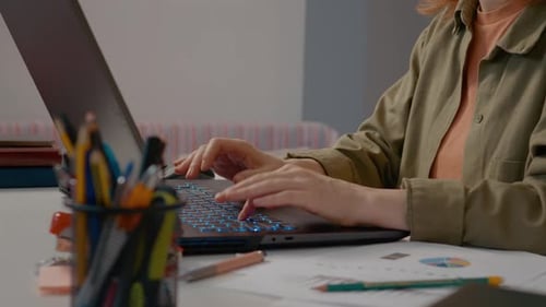 Young woman typing on a laptop in a well-lit home office workspace