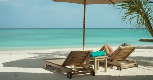 Close-up of Beautiful Blonde Female Lying on the Deck Chair on the Beach. Sunbathing on the Exotic