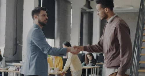 Men Partners Talking and Shaking Hands Standing in Shared Office Enjoying Successful Cooperation
