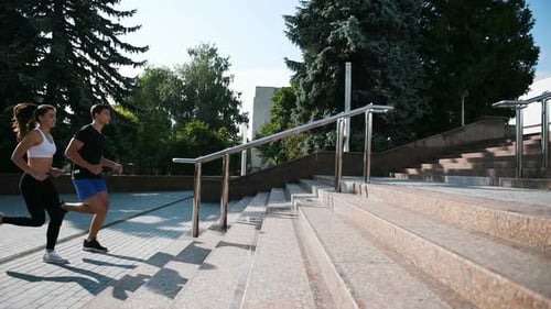 Side view of man and woman that have fitness day and running in the city up on the stairs