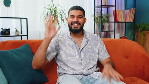 Man Waving Hello While Sitting on Couch