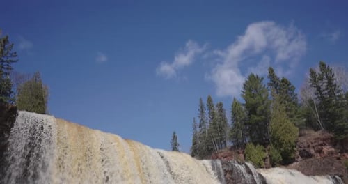 Cachoeira estrondosa em cascata sobre terreno rochoso entre a floresta