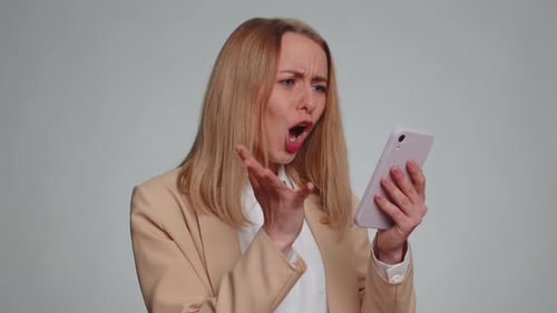 Woman Shocked by Phone on Gray Background