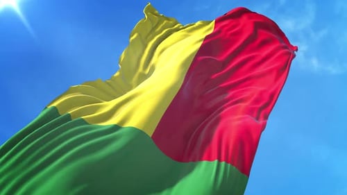 Realistic Waving Guinea Flag Against a Bright Blue Sky