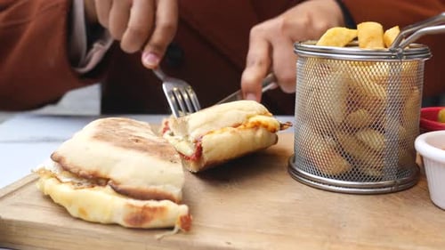 Cutting Panini Sandwich with Fries on Wooden Board