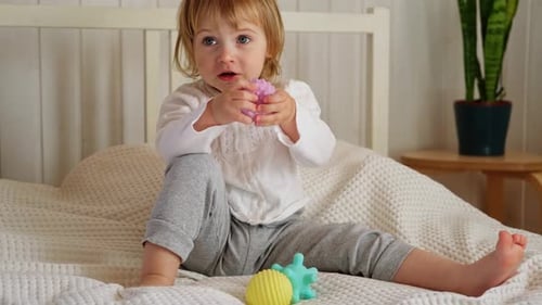 Happy Child Playing with Sensory Balls on Bed