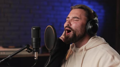Homme au casque chantant dans un microphone sur un studio d'enregistrement