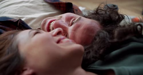 Close Up a Happy Brunette Guy with Curly Hair Lies on the Floor Head to Head with His Brunette