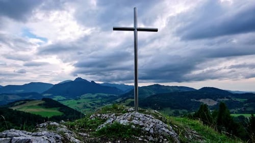 Timelapse of Cross on Rocky Summit with Rolling Hills in Background and Moving Clouds,4K