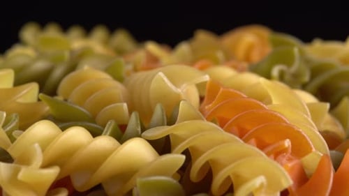 Pâtes italiennes multicolores Fusilli ou Rotini rotatives sur fond noir. Pâtes au blé dur