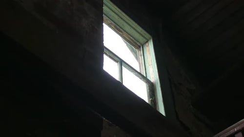 Eine Nahaufnahme eines offenen Fensters in einem verlassenen Haus.