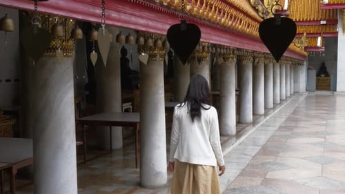 A woman walking along the holy bells at a temple in Bangkok, Thailand