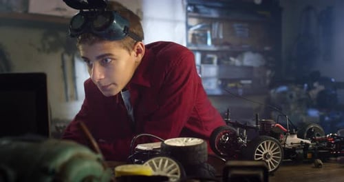 Portrait of Teenage Boy with Goggles in Workshop Working on Constructing a Functional Toy Car f