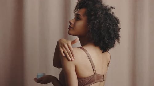 Body Care Cosmetics African American Lady Applying Cream on Her Shoulder Pampering Skin After Shower