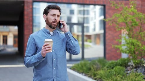 Businessman Talking on Phone Holding Coffee Near Office in City