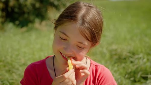Young Girl Eating Orange Slice Outdoors