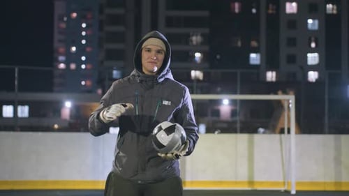 Young Boy Smiling While Holding Soccer Ball on Urban Sports Field