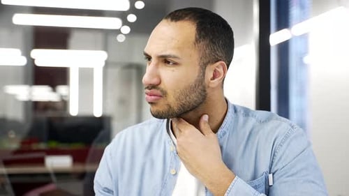 Sick Man Gripping Sore Throat in Office