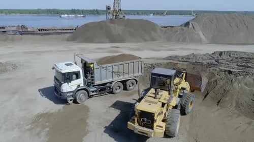 Heavy Machinery Filling a Dump Truck with Sand