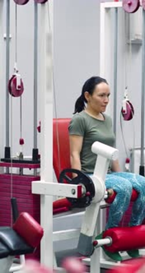 As extensões das pernas têm como alvo as pernas enquanto a mulher se exercita com determinação