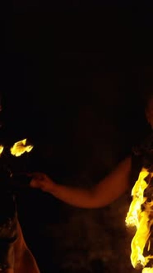 Dynamic Fire Performance in the Dark Featuring a Performer Skillfully Manipulating Blazing Flames