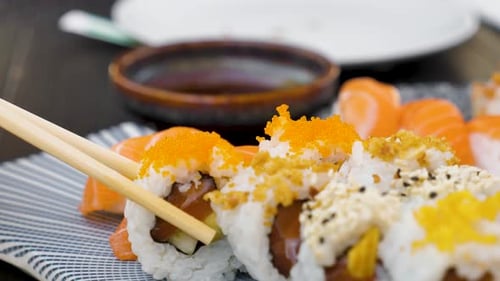 Sushi Rolls and Salmon Nigiri Being Eaten