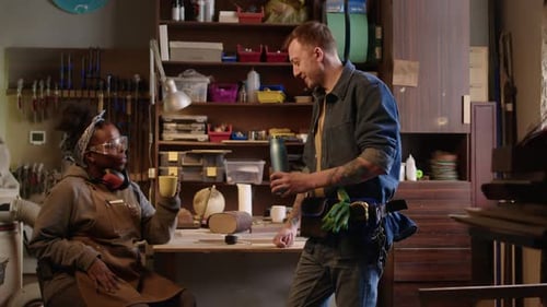 Two Tradespeople Chatting and Laughing in Workshop
